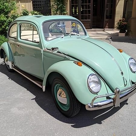 Ein türkiser VW Käfer steht auf einer Straße.