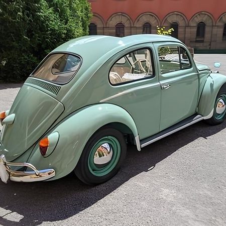 Ein türkiser VW Käfer steht auf einer Straße, Heckansicht.