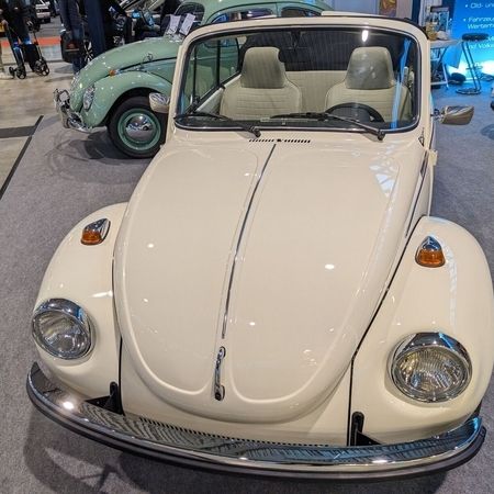Der VW Käfer Cabrio 1303 in Hellelfenbein in einer Halle, Fronansicht.
