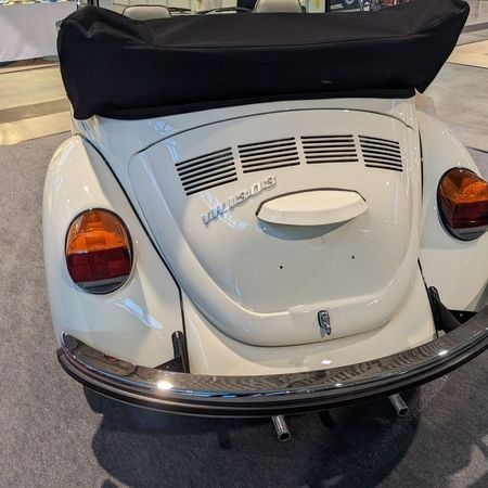 Der VW Käfer Cabrio 1303 in Hellelfenbein in einer Halle, Heckansicht.