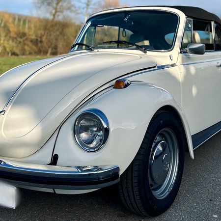 Der VW Käfer Cabrio 1303 steht auf einer Straße, Frontansicht.