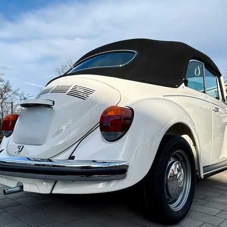 Der VW Käfer Cabrio 1303 steht auf einer Straße, Heckansicht.